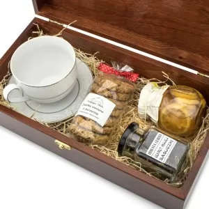 drewniana skrzynka z filiżanką, herbatą, ciastami i syropem na prezent dla wychowawczyni